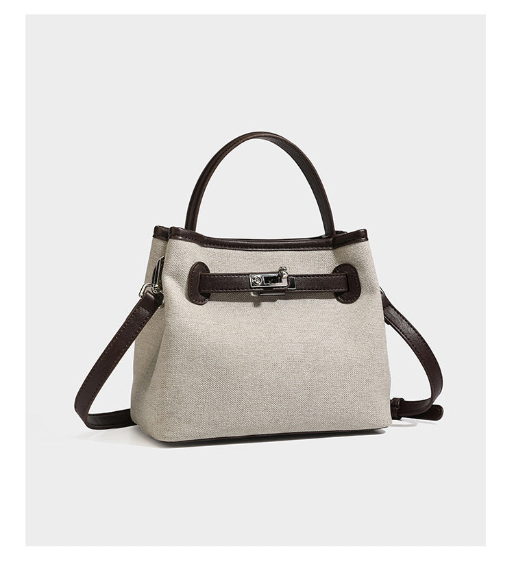 Small structured beige canvas top-handle bag with dark brown leather-look trim, silver turn-lock hardware, and detachable