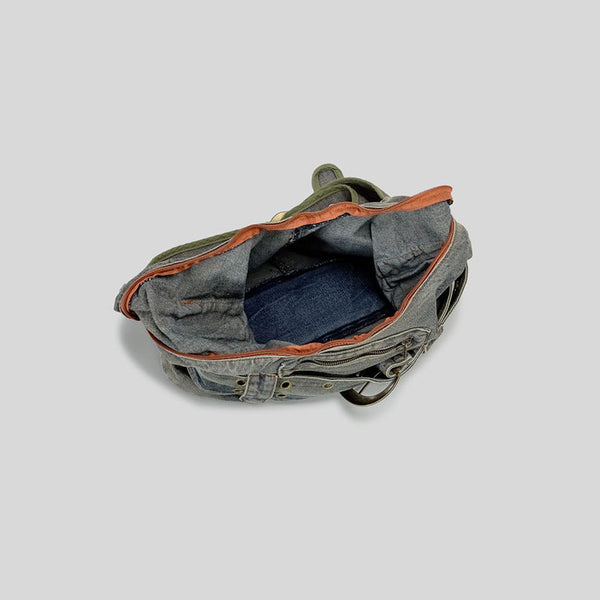 Washed blue-gray denim slouchy hobo shoulder bag with wide grommeted belt panel, brass-tone D-ring buckle, exterior zip
