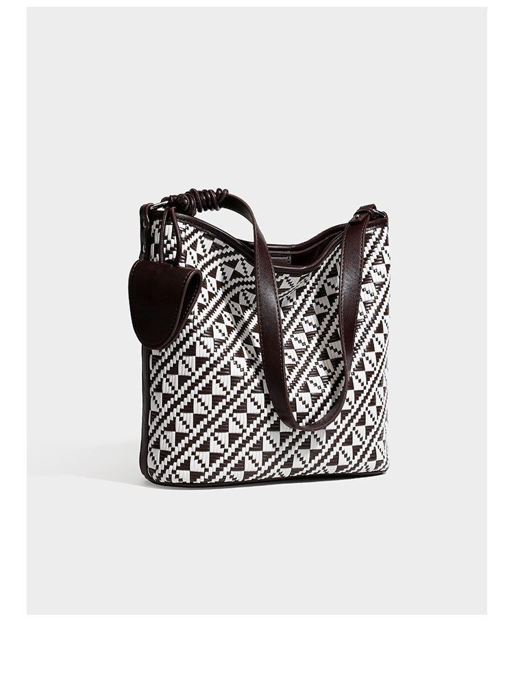 Geflochtene Schultertasche mit geometrischem Ethno-Muster, Besatz in dunkelbrauner Lederoptik, langem verstellbarem Träger und kleinem hängendem Reißverschluss
