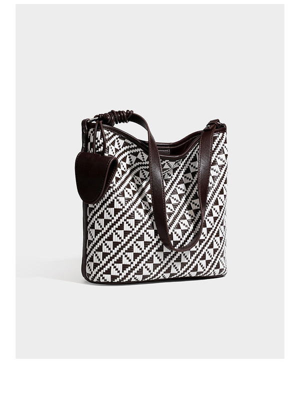 Geflochtene Schultertasche mit geometrischem Ethno-Muster, Besatz in dunkelbrauner Lederoptik, langem verstellbarem Träger und kleinem hängendem Reißverschluss