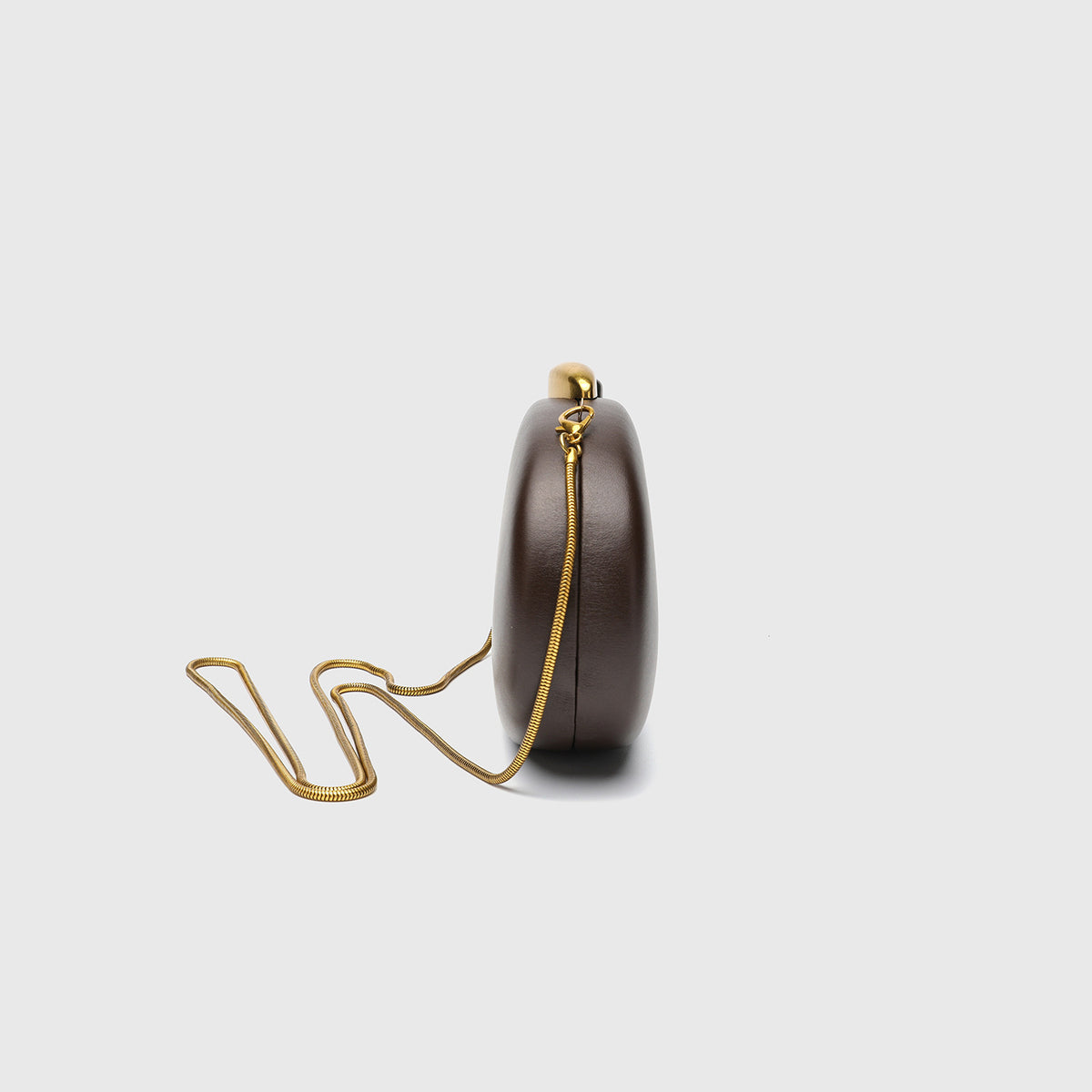 Oval hard-shell crossbody clutch bag with smooth matte leather-look finish and gold-tone snake chain strap, detail view 2