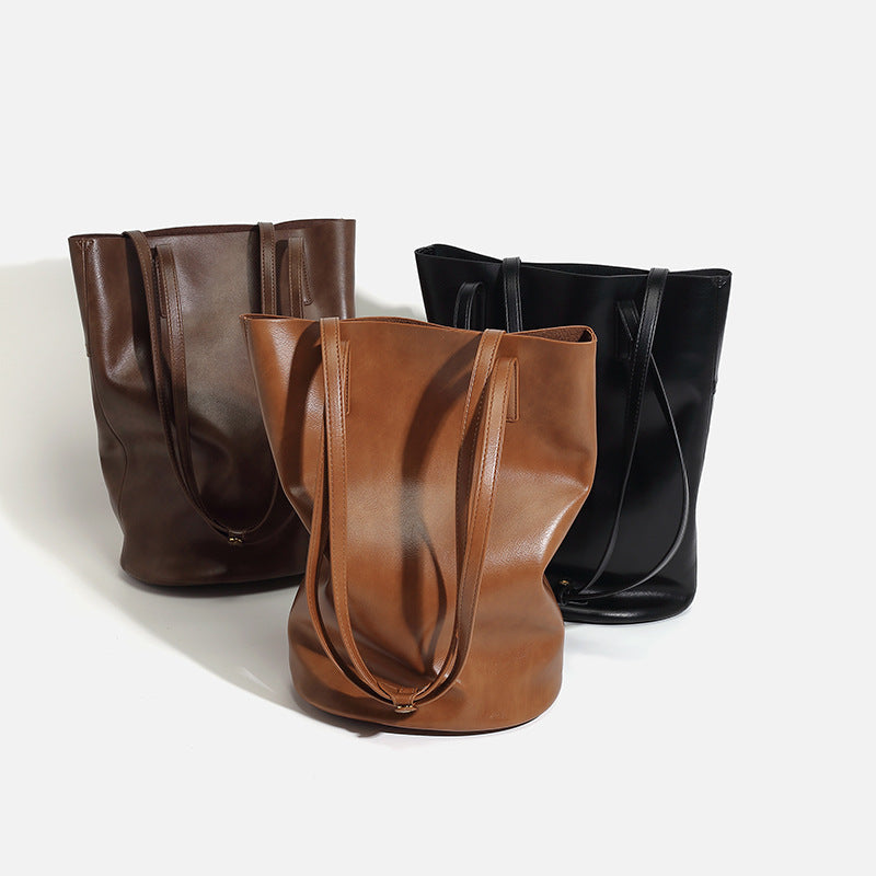Large black smooth leather-look bucket tote bag with long shoulder straps and open top, detail view 4