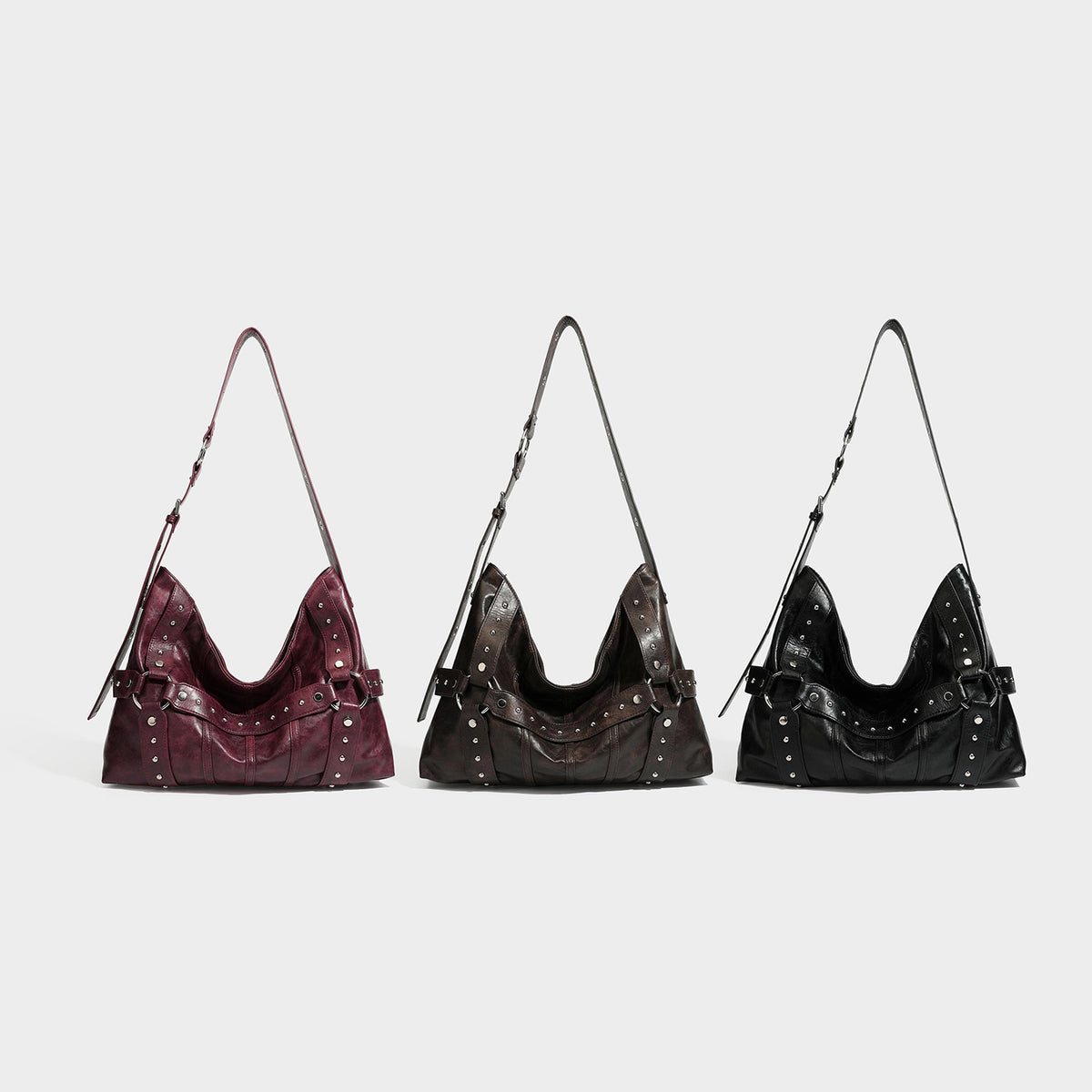 Slouchy hobo shoulder bag in glossy leather-look finish with silver-tone rivets, buckle strap detail, and zip-top closure
