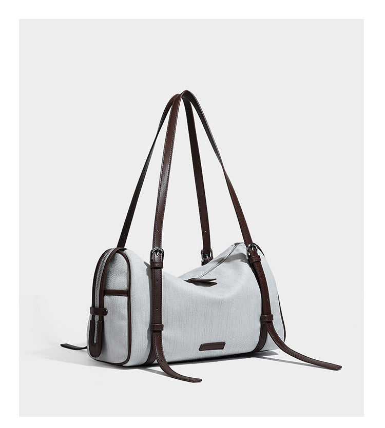 Olivgrüne Schultertasche in Zylinderform aus Canvas mit Riemen in schwarzer Lederoptik, Reißverschluss oben und silberfarbenen Beschlägen, Detailansicht