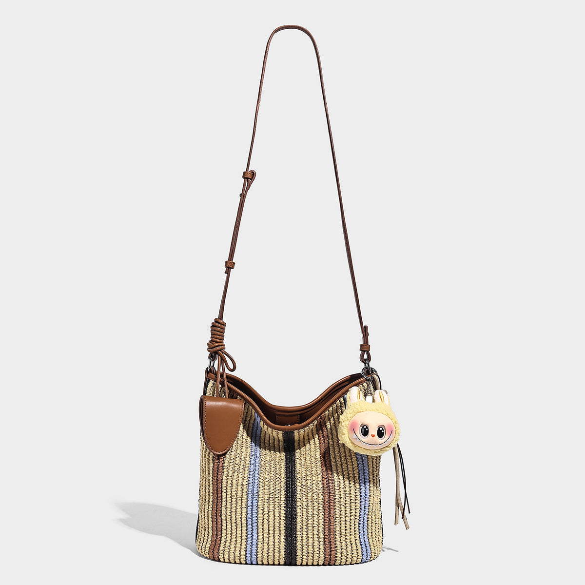 Striped woven straw-style shoulder bag with tan leather-look trim and long adjustable strap, detail view 2