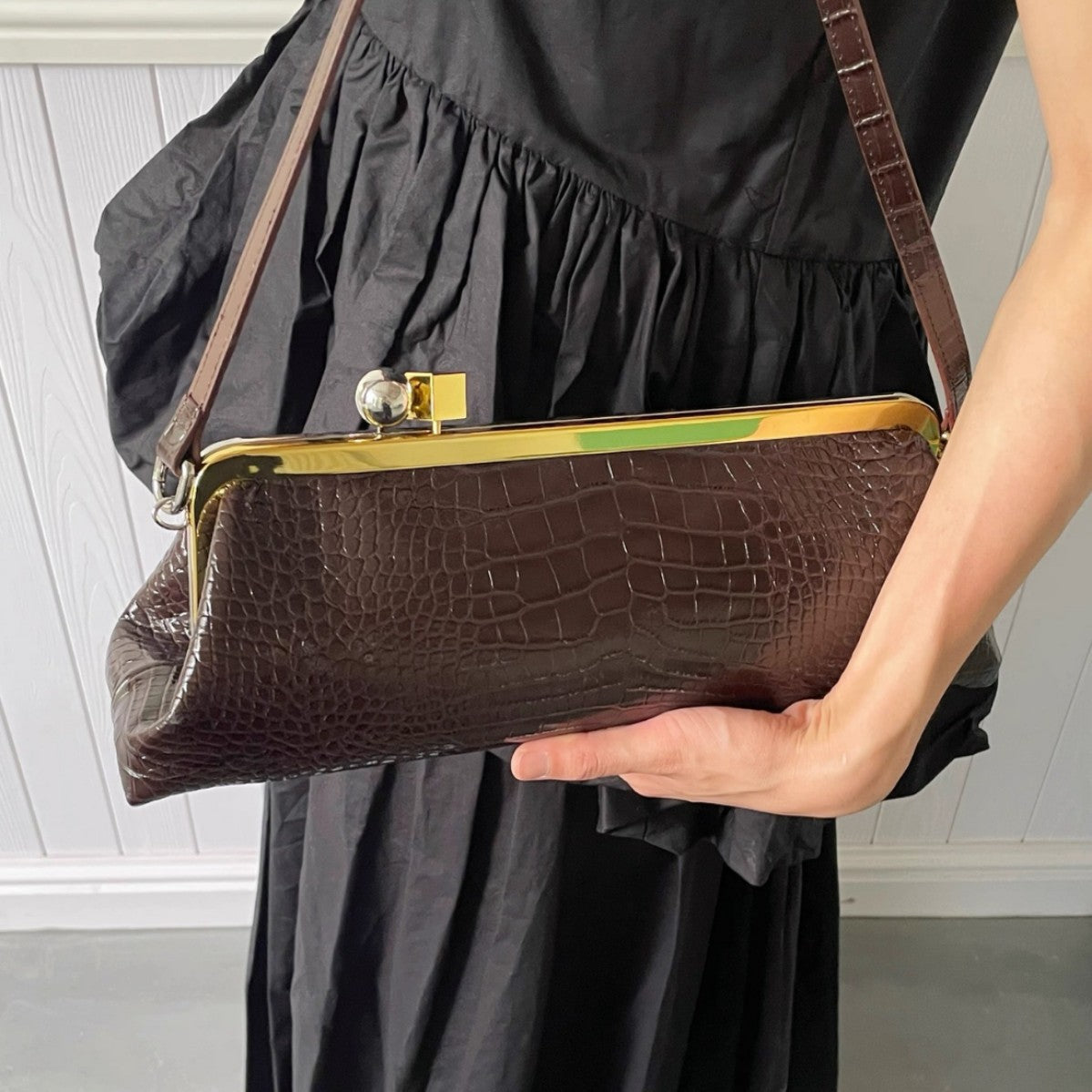 Structured kiss-lock frame clutch bag in dark brown crocodile-embossed leather-look finish with gold-tone hardware and slim