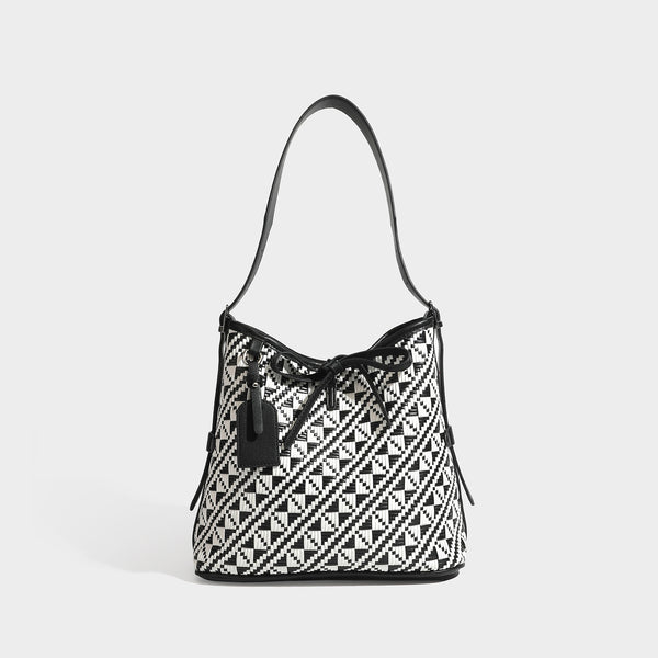 Woven geometric bucket shoulder bag in white and dark brown two-tone pattern with leather-look trim and drawstring top