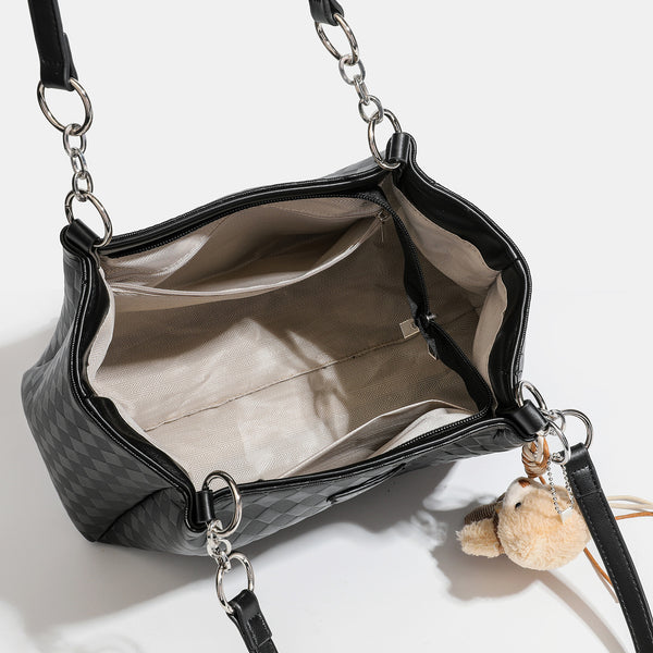 Black diamond-quilted leather-look tote bag with silver chain-ring shoulder straps and plush bear charm pendant, detail view