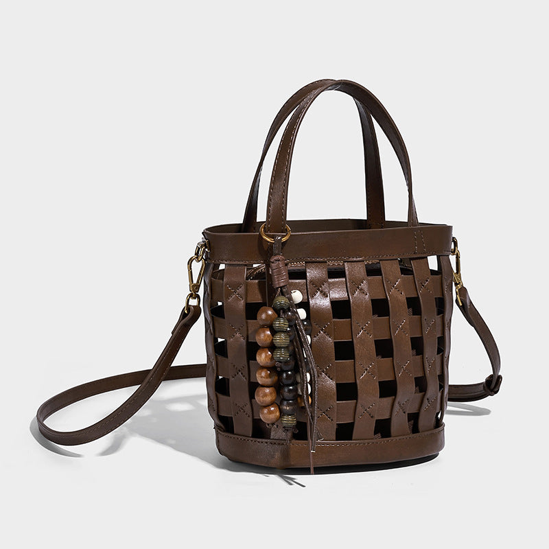 Small woven lattice bucket bag in brown leather-look finish with beaded tassel charm, dual top handles, and detachable, front