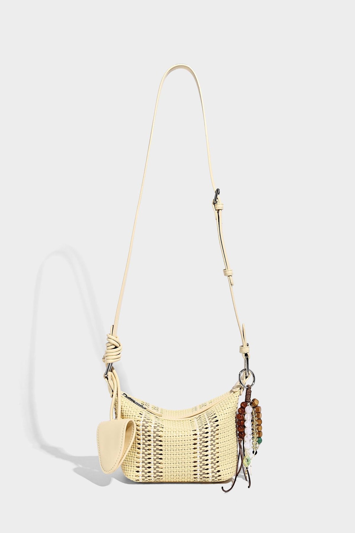 Small woven crescent shoulder bag with leather-look trim, zip closure, silver-tone ring hardware, and beaded tassel charm