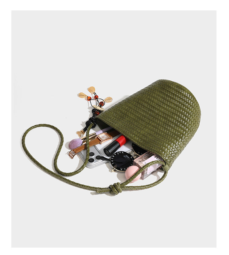 Olive green woven leather-look bucket bag with braided crossbody strap, knotted adjustment, and gold-tone tassel charm with