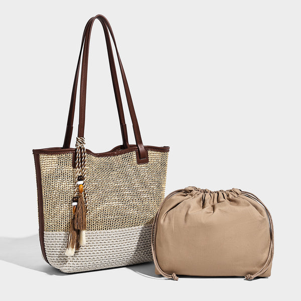 Woven beige and cream tote bag with brown leather-look trim, long double shoulder straps, and knotted tassel charm on front