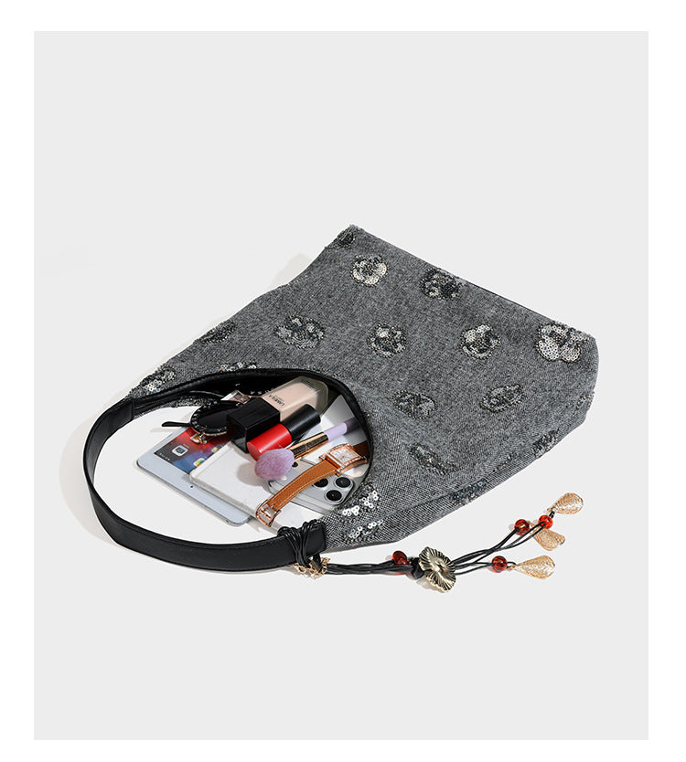 Lässig fallende, trapezförmige Schulter-Tote in Anthrazitgrau mit floralen Paillettenmotiven in Silber, Riemen in Lederoptik und herabhängendem Perlenbesatz
