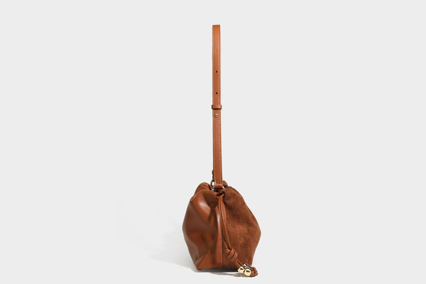 Suede-look drawstring shoulder bag in brown with smooth trim, knotted bead drawstring closure, slim adjustable strap, and