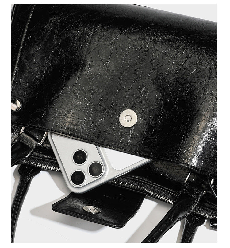 Structured glossy crinkled leather-look satchel with double top handles, front metal-plaque tab, silver-tone hardware, and