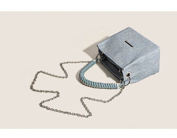 Small structured trapezoid mini bag with coiled rope top handle and silver-tone chain strap in textured fabric, detail view 8