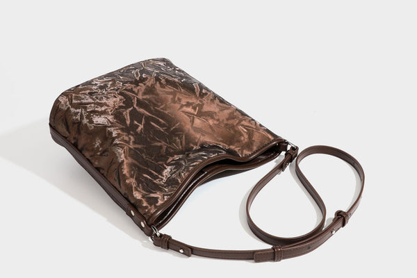 Große Hobo-Schultertasche mit Crinkle-Glanzfinish in Dunkelbraun, schmalem verstellbarem Riemen, geknoteten Beschlägen und seitlich befestigter Klappe
