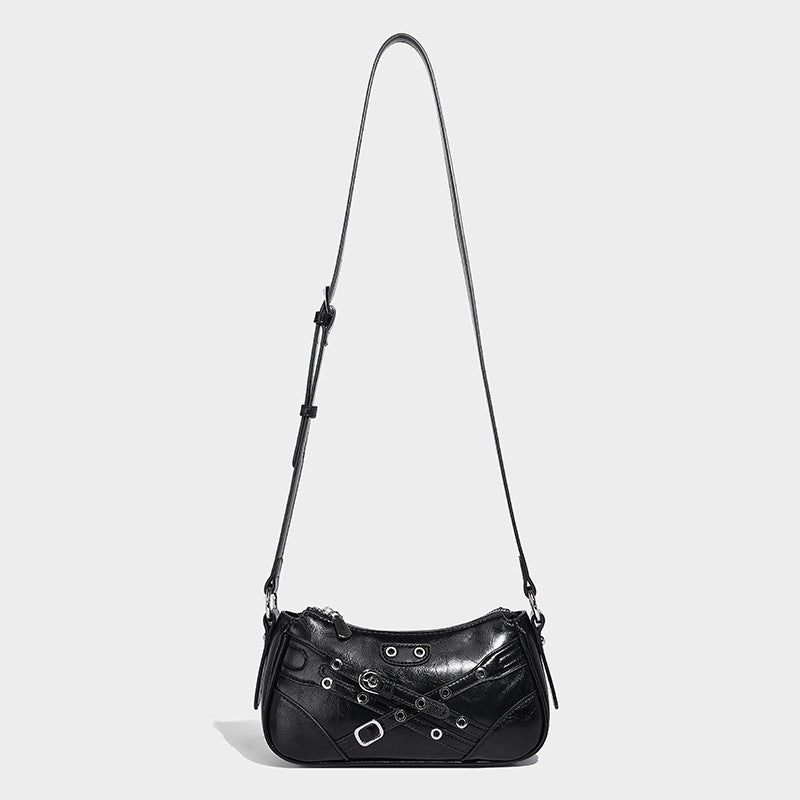 Compact moto-inspired shoulder bag with crisscross grommet strap detail, glossy textured finish, and adjustable crossbody