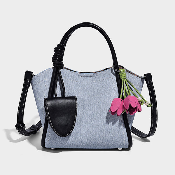 Structured canvas tote bag with knotted top handles, leather-look black trim, front flap pocket, and pink tulip flower charm