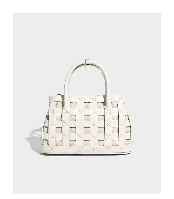 Small structured woven satchel tote with rounded top handles, silver-tone ring hardware, and bead tassel charm, detail view