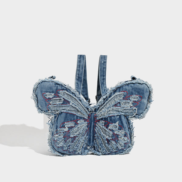 Butterfly-shaped distressed denim shoulder bag with frayed raw edges and embroidered wing panels, front view