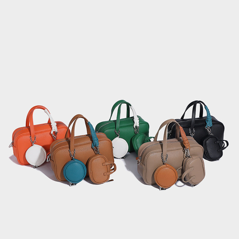Structured pebbled leather-look Boston bowling bag in tan with blue detachable round mini pouch, dual top handles, and