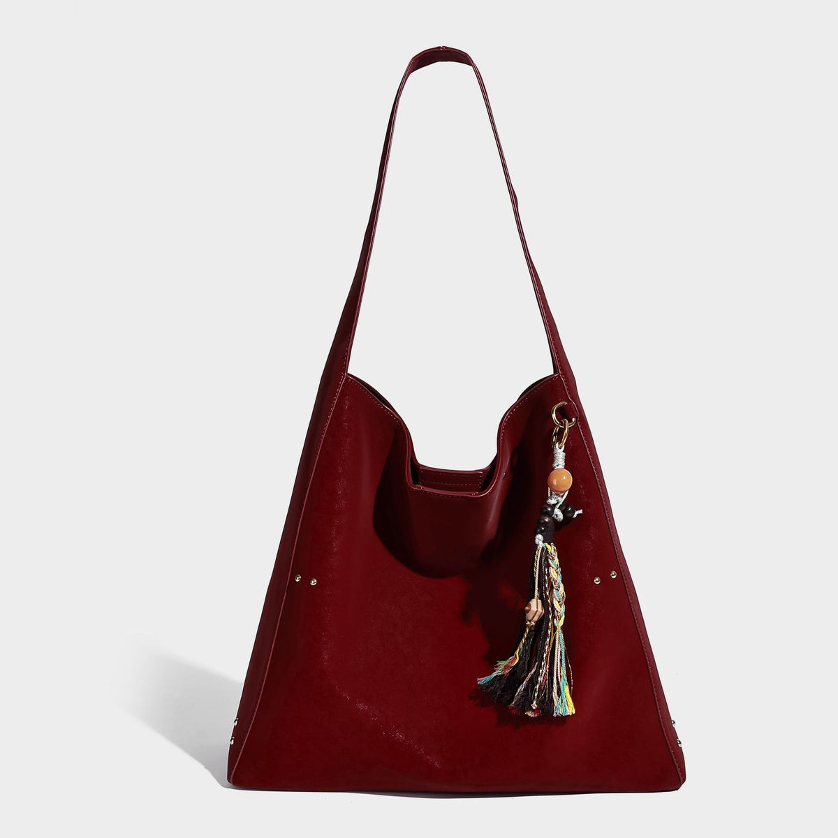 Oversized trapezoid tote bag with matte leather-look finish, gold-tone rivets, and long shoulder strap, detail view 8