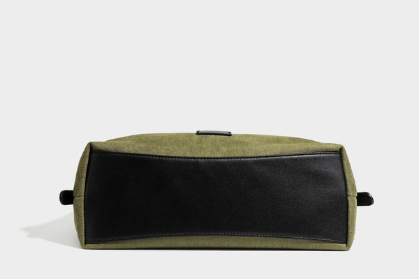 Slouchy olive green canvas hobo shoulder bag with black leather-look trim, zip-top closure, and adjustable strap, detail view
