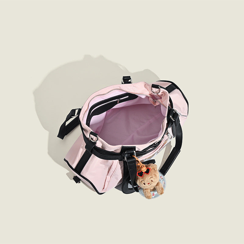 Pale pink nylon tote bag with black leather-look trim, double top handles, side zip pocket, and detachable crossbody strap