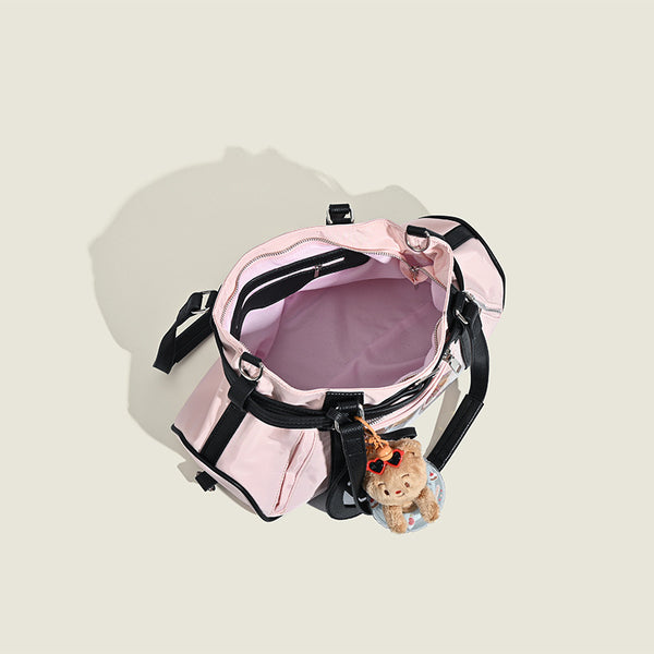 Pale pink nylon tote bag with black leather-look trim, double top handles, side zip pocket, and detachable crossbody strap