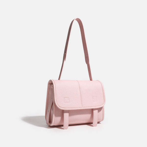 Compact structured flap satchel bag with pebbled texture, snap closure, front strap tabs, and long adjustable crossbody