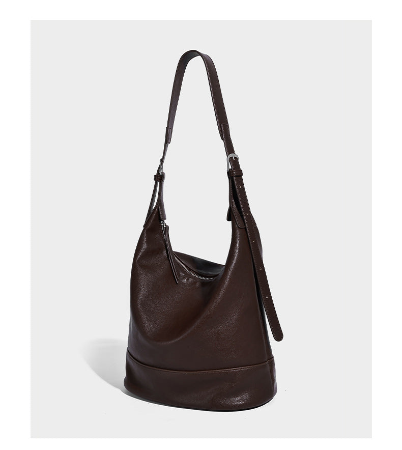 Slouchy bucket hobo shoulder bag in dark brown with glossy leather-look finish, top zip closure, and long adjustable, detail