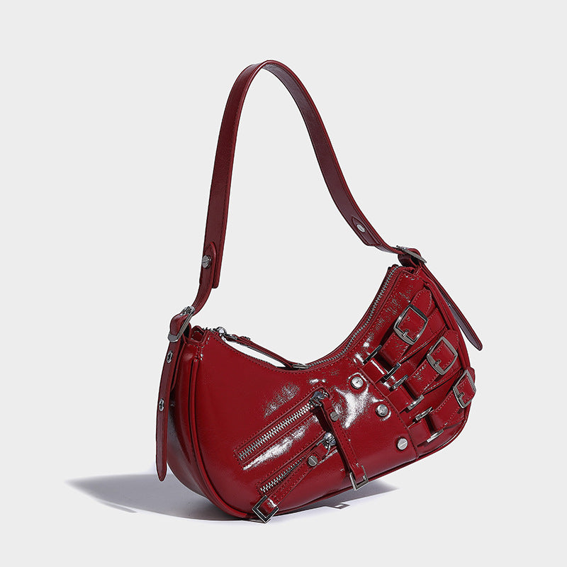 Crescent shoulder bag in washed blue denim-look PU with stacked buckle straps, front zip pocket, and silver-tone hardware