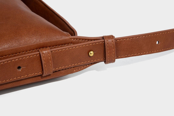 Slouchy brown leather-look shoulder bag with knotted drawcord tie closure, gold-tone ring hardware, and long adjustable