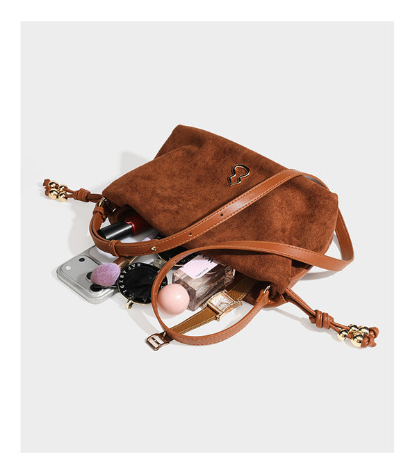Suede-look drawstring shoulder bag in brown with smooth trim, knotted bead drawstring closure, slim adjustable strap, and