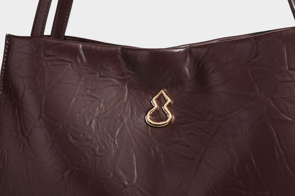 Strukturierte rechteckige Tote-Schultertasche aus glänzender, geknitterter Lederoptik mit langen Doppelträgern und Emblem in Goldoptik