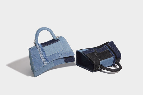 Structured patchwork denim trapezoid satchel bag with frayed panel trim, rounded top handle, and silver-tone hardware, detail