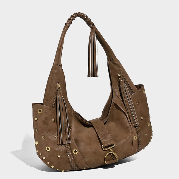 Slouchy crescent hobo bag in matte brown suede-like finish with gold-tone studs, grommets, braided top handle, tassel side