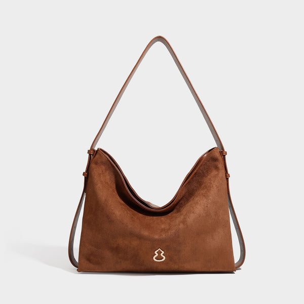 Slouchy suede-finish brown shoulder bag with long single strap and small gold-tone logo emblem on front, front view