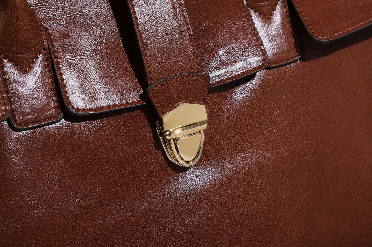 Strukturierte Henkeltasche in glänzender Lederoptik mit Überschlagverschluss, mittigem Riemen, goldfarbenem Drehverschluss und zwei Henkeln