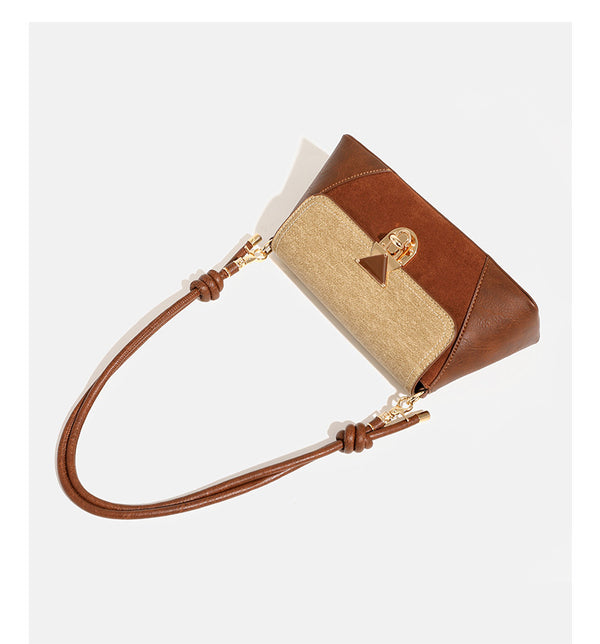 Structured trapezoid shoulder bag with pale textured flap, gold-tone triangular turn-lock closure, and long knotted cord