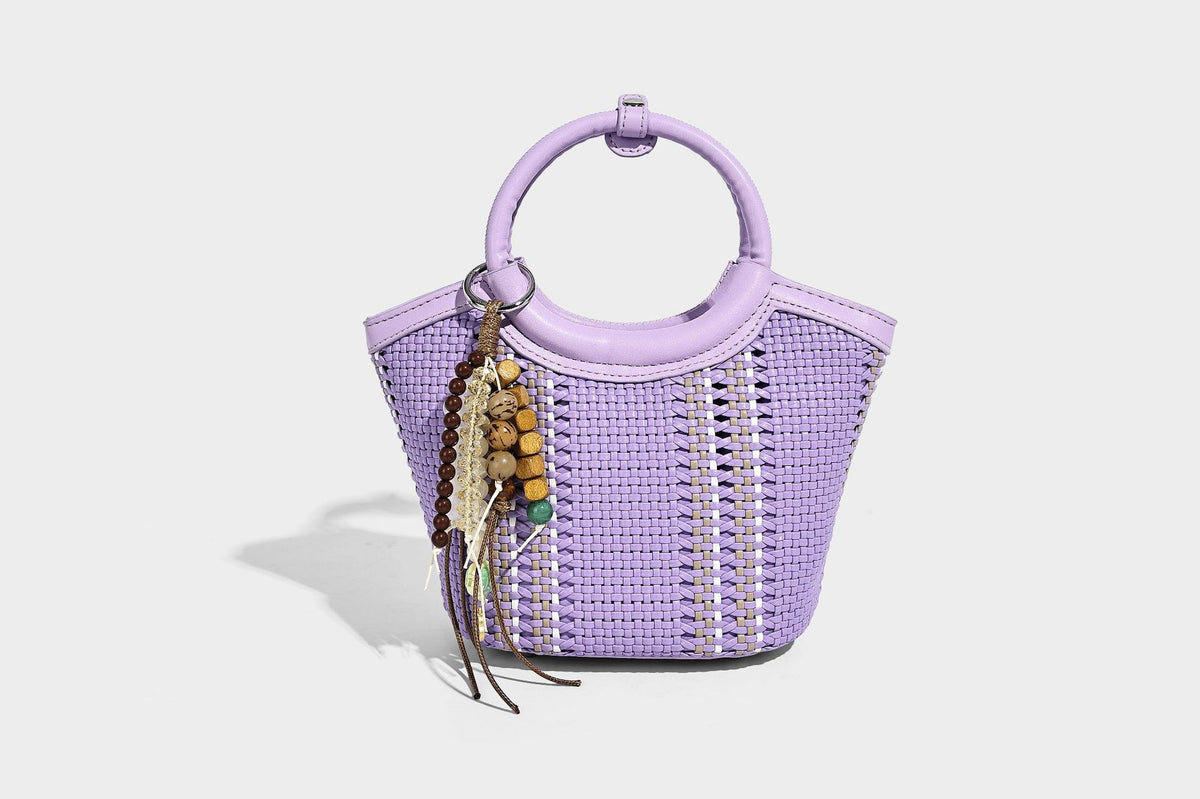 Kleine strukturierte Beuteltasche aus geflochtenem Material mit rundem Tragegriff in Lederoptik, silberfarbenen Beschlägen und perlenbesetztem Quastenanhänger, Detail