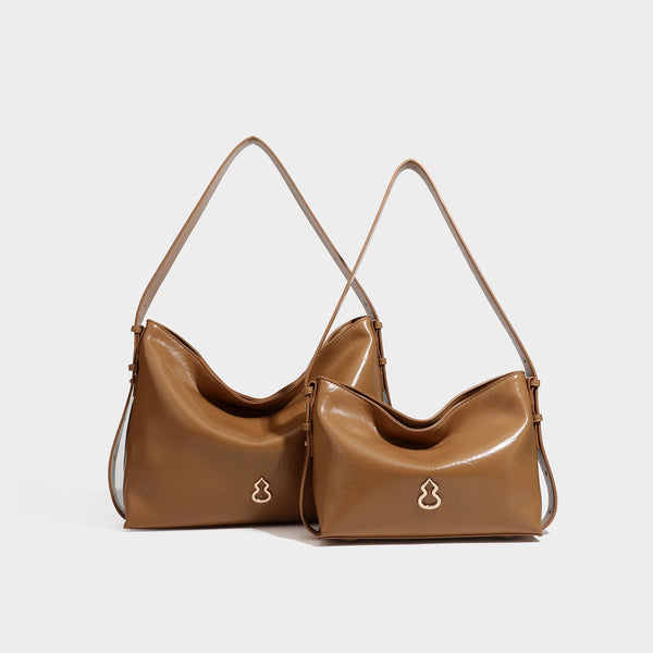 Lässig fallende Hobo-Schultertasche mit offenem Oberteil aus glänzender, karamellbrauner Lederoptik, mit Logo-Beschlägen in Goldoptik und langem, verstellbarem