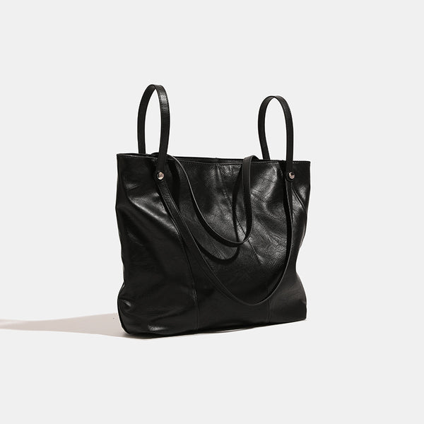 Große quadratische Shopper-Tasche in schwarzer Lederoptik mit zwei Schultergriffen und längerem Trageriemen, glatte glänzende Oberfläche und seitliche Beschläge