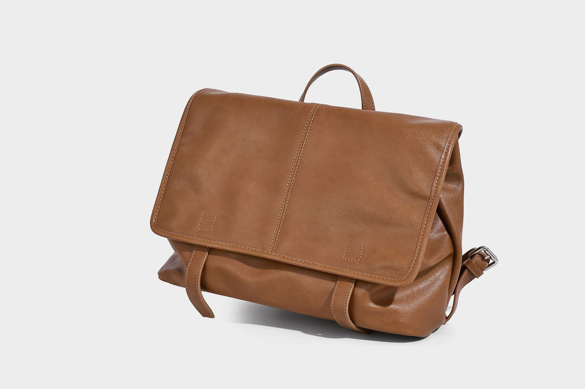 Structured tan leather-look flap backpack handbag with top handle, silver buckle hardware, and fold-over front closure