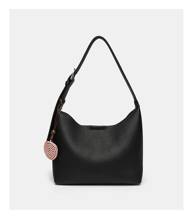 Slouchy hobo shoulder bag in pale yellow pebbled texture with woven charm, adjustable strap, matching zip pouch, and, detail