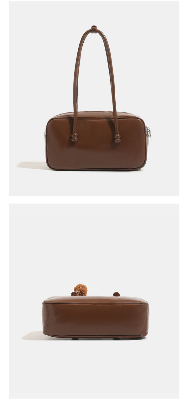 Kastige, rechteckige Bowling-Schultertasche mit glänzender Lederoptik, zwei abgerundeten Trageriemen, Reißverschluss an der Oberseite und abnehmbarer