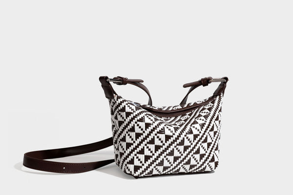 Kleine schwarz-weiße Schultertasche mit gewebtem geometrischem Muster, glatter dunkelbrauner Besatz aus Lederoptik, geknotetem verstellbarem Riemen und seitlichem