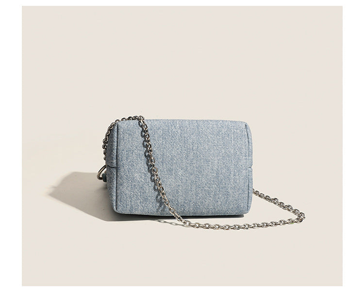 Small structured trapezoid mini bag with coiled rope top handle and silver-tone chain strap in textured fabric, detail view