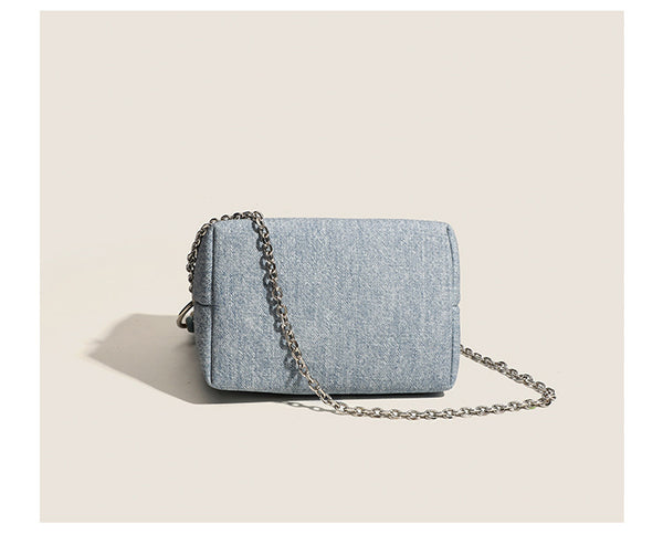 Small structured trapezoid mini bag with coiled rope top handle and silver-tone chain strap in textured fabric, detail view